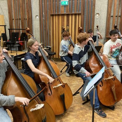 A room of students sat next to one another playing the double bass